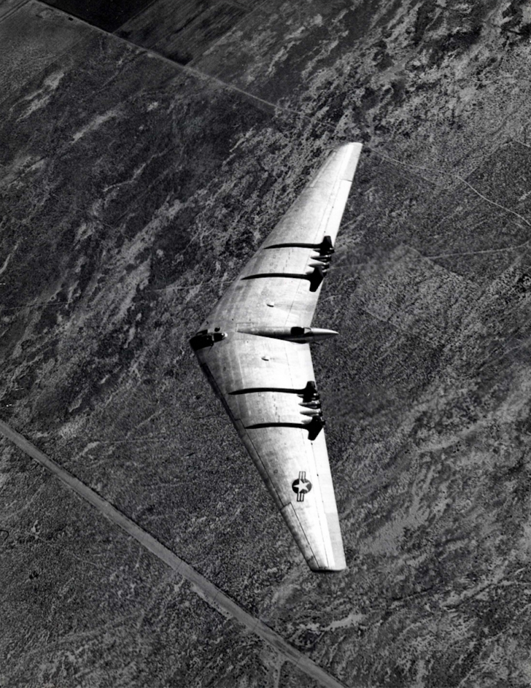 Northrop YB-49 Flying Wing in flight over desert terrain, photographed from directly above showing the wing planform