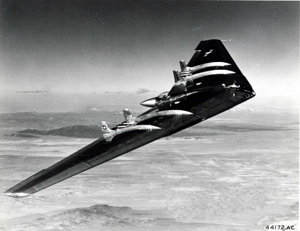 Northrop YB-49 Flying Wing in flight over mountainous terrain, banking to show the dramatic wing profile against the sky